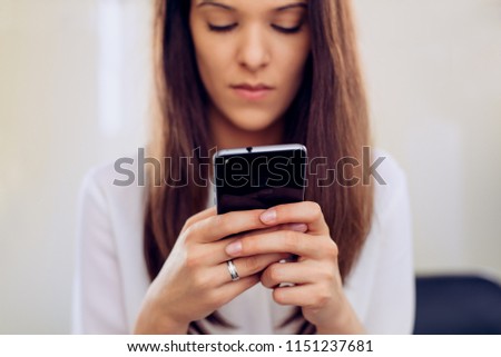 Businesswoman in her office with smartphone texting