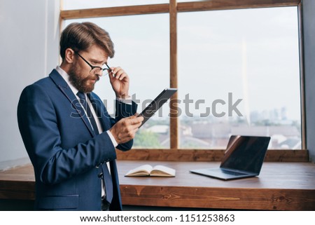 business man in glasses near the window looks at the tablet                           
