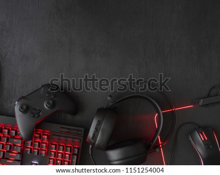 gamer workspace concept, top view a gaming gear, mouse, keyboard, joystick, headset, mobile joystick, in ear headphone and mouse pad on black table background with copy space. Royalty-Free Stock Photo #1151254004