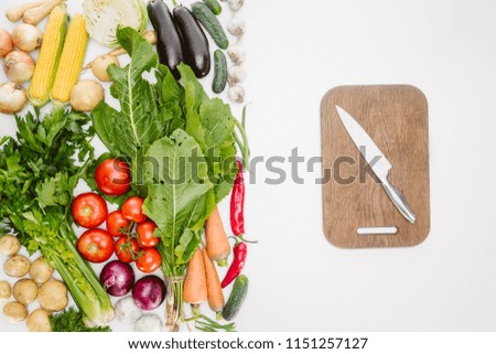 flat lay with ripe autumn vegetables and wooden cutting board with knife isolated on white