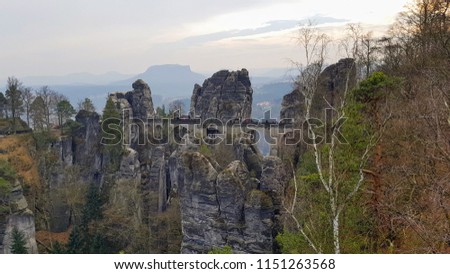 Top view panorama of Germany Elbe Sandstone Mountains rock formation and cliffs in the spring with Elbe Valley river curve and snow in the background, Bastei stone bridge in Saxon Switzerland