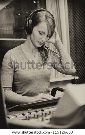 Portrait of female dj working in front of a microphone on the radio. Black and white