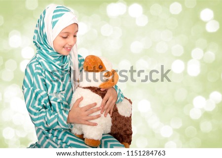 Happy little girl playing with her sheep toy - celebrating Eid ul Adha - Happy Sacrifice Feast Royalty-Free Stock Photo #1151284763