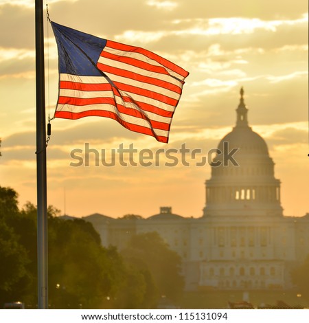 United States Capitol building silhouette and US flag at sunrise - Washington DC Royalty-Free Stock Photo #115131094