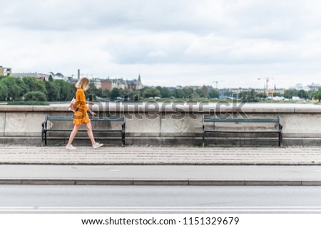 Young fashionable woman walking on the Queen Louise Bridge over Peblinge So. Traditional danish architecture of Copenhagen, Denmark Royalty-Free Stock Photo #1151329679