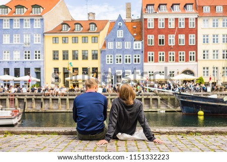 Tourists enjoying the scenic summer view of Nyhavn pier. Colorful building facades with boats and yachts in the Old Town of Copenhagen, Denmark Royalty-Free Stock Photo #1151332223