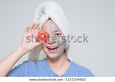 cute young Asian teenage girl hold tomato, smile happy face masking cream on face and towel on her head. woman beauty shot with idea of skin care nutrition, suitable for skin care and cosmetic product