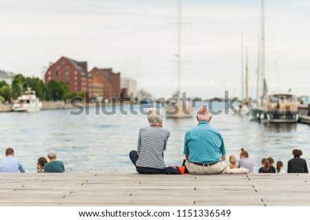 Senior couple enjoying a relaxing summer day in the Copenhagen port with boats and yachts in the Old Town. Concept of hygge. Royalty-Free Stock Photo #1151336549