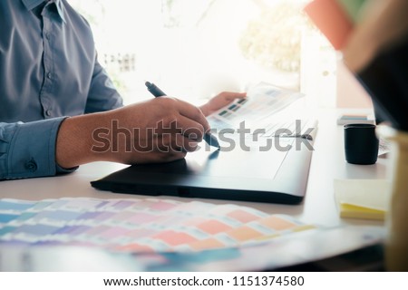 Graphic designer and Photographer working on computer and used graphics tablet.