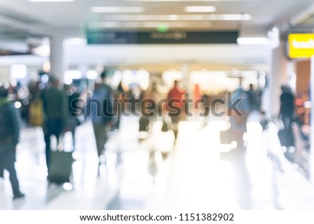 Motion blurred motion people walking with luggage at American airport. Abstract blurry passengers or tourist with bag, back view. Defocused traveler away at hallway terminal, morning lights backlit