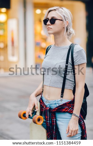 Portrait of young hipster woman with skateboard