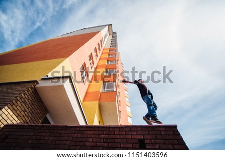 Teenage boy on a street in a big city next to a high-rise building alone. concept of a teenager parkour life. height standing portrait on a high-rise building background close