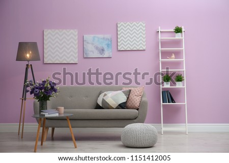 Modern living room interior with comfortable gray sofa near color wall