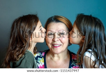 Little beautiful granddaughters kiss their beloved grandmother on both sides