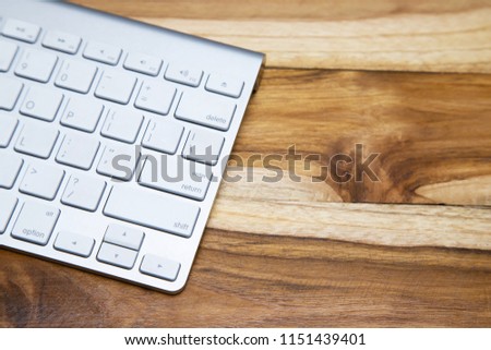 Modern aluminum computer keyboard of a laptop on on the desk office wooden.  Top view.