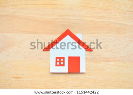 Paper cut of house red roof on brown wood background,top view. 