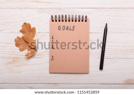 Autumn leaves, notebook and pencils on a white wooden background. Flat lay, top view, copy space.