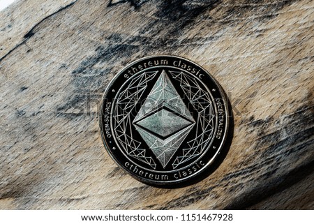 One golden Ethereum cryptocurrency coin on a background of grained wood.