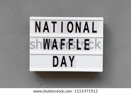 'National Waffle Day' word on lightbox over concrete background, top view. From above, overhead.