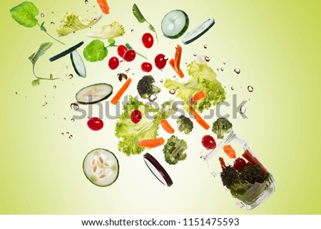 Salad in the pot with all ingredients floating out of the pot on green gradient background and splashing water
