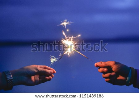 Abstract blur beautiful sparklers Motion by wind blurred man and woman 2hand holding burning sparkle on nature for celebration background with dark blue twillight sky.Vintage film grain filter tone.