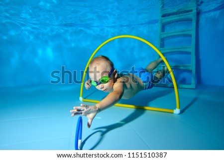 A little boy is engaged in scuba diving in the pool and dives to the bottom for toys. Portrait. Shooting underwater. Horizontal orientation.