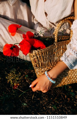 Young countryside girl with long blond hair wearing straw hat  in the field of poppies