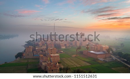 A scene taken from height to " Nidah " village in Sohag-Egypt during sunrise in a foggy day. The picture shows the big mountain that limits the grand Nile valley from the east.