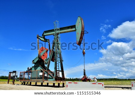 An image of an old oil and gas pump jack on a sunny summer day. 