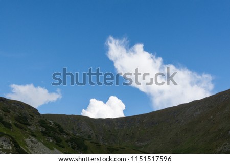 clear composition - white clouds, blue sky, dark mountain