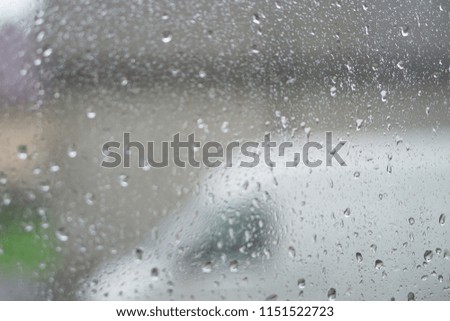Rainy, autumn weather outside the window. Drops of water on the glass on a blurred background. Romantic grubby topic. Stock photo for design