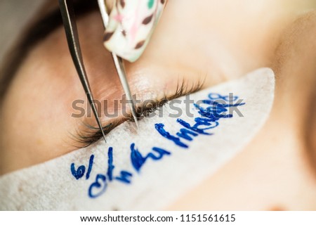 Artificial eyelash extensions in the master of eyelash extensions in the beauty salon, medical tweezers and special glue for the coupling of artificial eyelashes with real