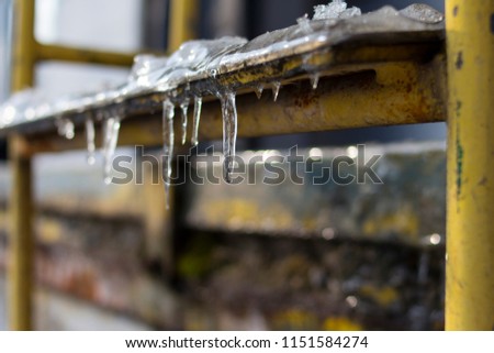 Ice and icicles on old rustic yellow stair steps outside slipping hazard risk