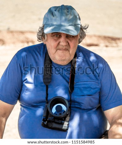 An elderly professional photographer takes pictures in nature