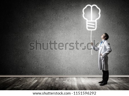 Professional medical industry employee in white medical suit interracting with glowing screw symbol in the air while standing against gray wall on background.