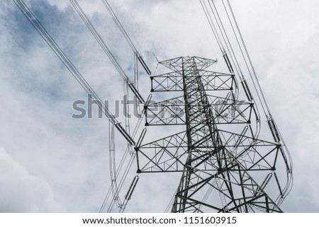 High voltage towers with blue backdrops and clouds.