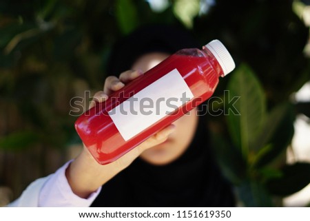 juice bottle label. Attractive woman holding plastic bottle with fresh pressed orange carrot juice.
