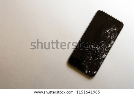 Broken screen cell phone on gray background.
Smartphone Insurance and Mobile phone warranty concept.
top view.