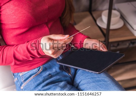 women pay with a credit card on a tablet.