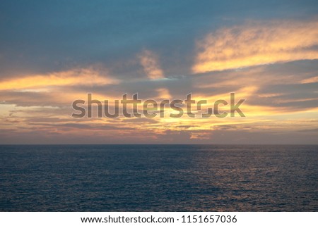 Twilight sunset over the sea with colorful clouds. Dramatic ambience created by the sunlight. Sun rays through dark clouds of stormy sky. High resolution panoranic photography.