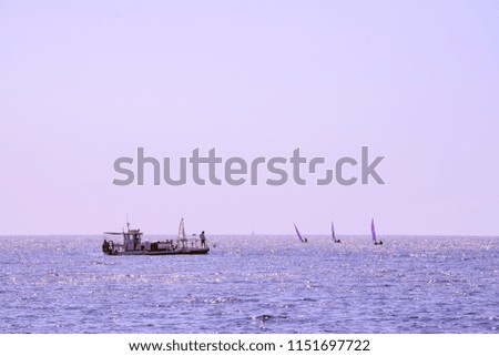 A boat cleans the sea white sailboats cross in the the background