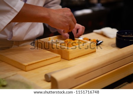 Professional and experienced sushi chef is carefully spoon a delicate and top quality uni or sea urchin to make sushi. Precision and Finesse at its best practice to achieve top performance in business