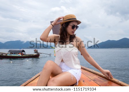 Front face view of the young woman wear hat with sunglasses in relax outside on the boat and looking at the sea view.