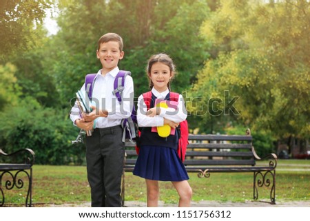 Cute little school children with stationery in park