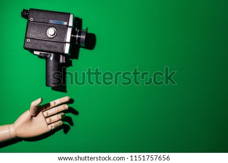 A wooden hand stretches toward the camera against a background of green background. Video production. Chromakey. Close-up. Space for text. Vertical