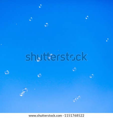 Soap bubbles in flight against the blue sky .
