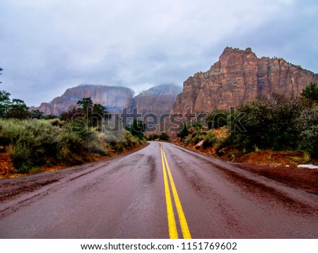 Way to the valley Zion Park. USA. Wet road and yellow streak. Canyons.