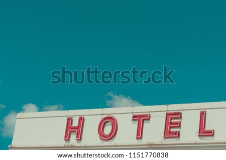 Hotel vintage neon sign text on old building with sky copy space retro color stylized 