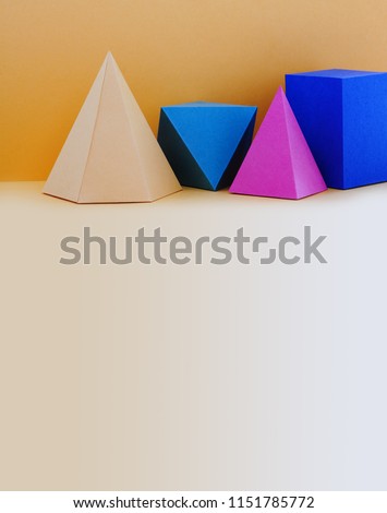 Colorful abstract geometrical composition. Three-dimensional prism pyramid rectangular cube objects on yellow background. Yellow blue pink green colored solid figures. copy space.