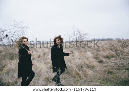 curly-haired adult son and mom with dry grass in hands on the field background